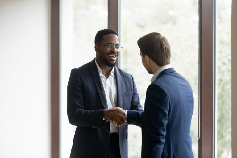 Overjoyed multiethnic businessmen shake hands greeting getting acquainted in office, smiling diverse multiracial male business partners handshake close deal make agreement after successful negotiation