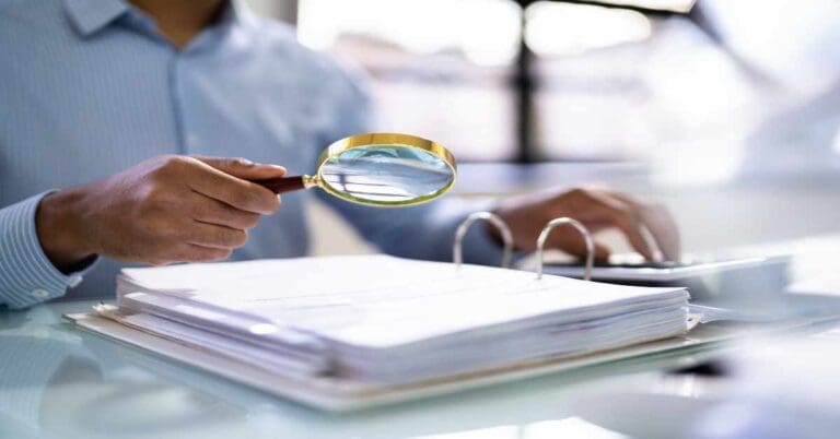 Auditor Using Magnifying Glass For Audit And Fraud Investigation