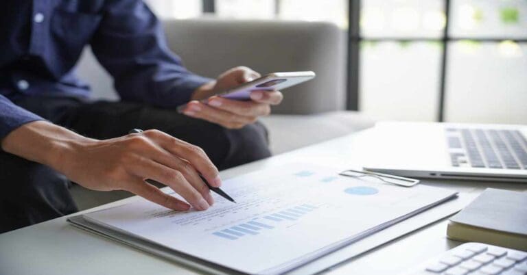 Man calculates the finances by smartphone at home, He sitting on sofa in living room at home.