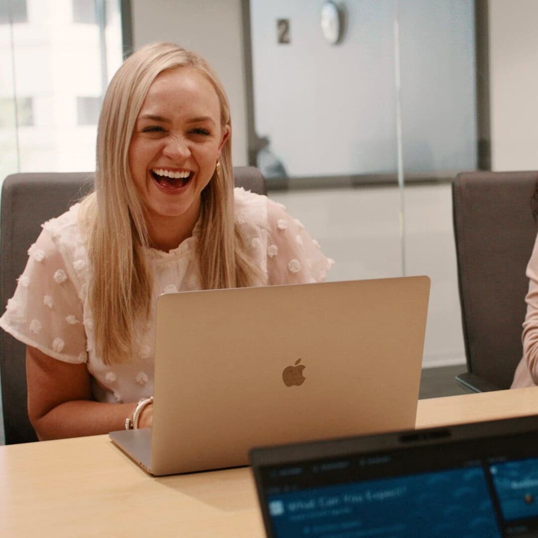 Female worker with her laptop laughs while in a conference room.